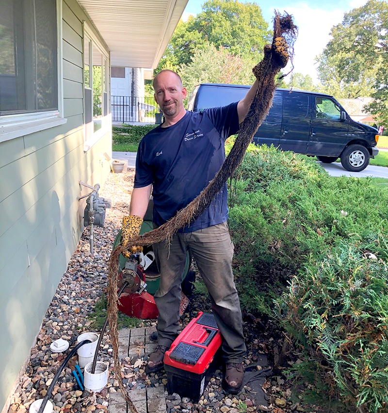 The Sewer Dude, Rod Johnson, holding a root that was pulled out of a main line drain